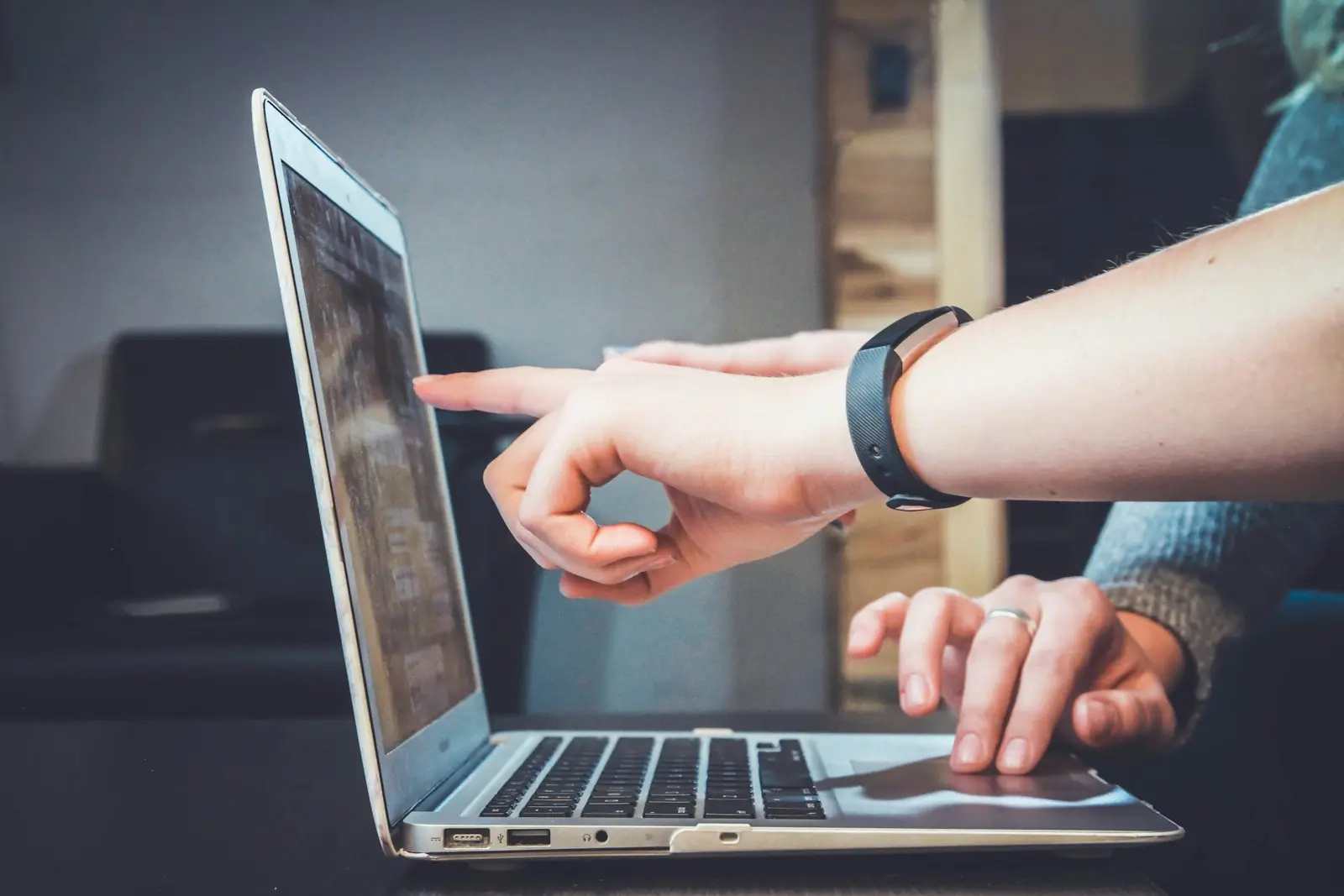 a hand pointing at a laptop screen