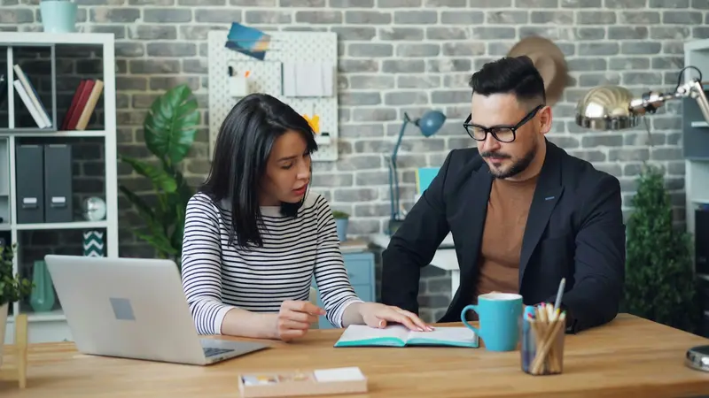 two colleagues working at one laptop